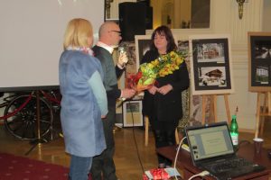 Radni RM Małgorzata Pachota i Adam Jennings wręczają Iwonie Czech wiązankę kwiatów